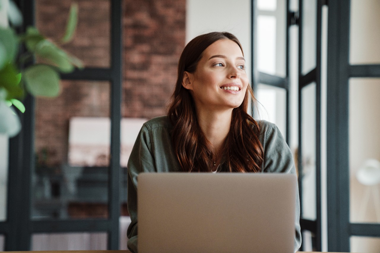 Beautiful smiling woman working with laptop while sitting at table