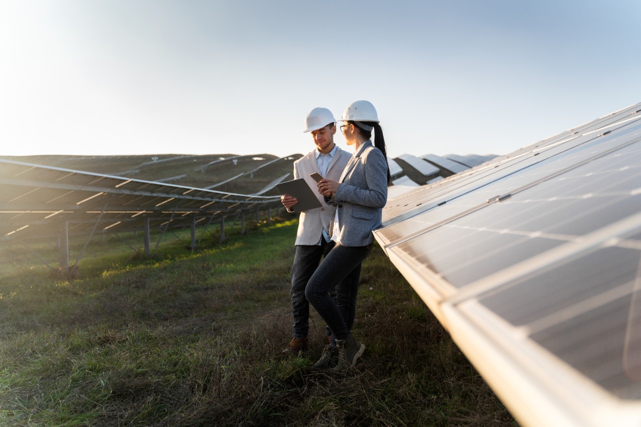 Elegant woman and business man are talking about scheme of solar panels in the meadow